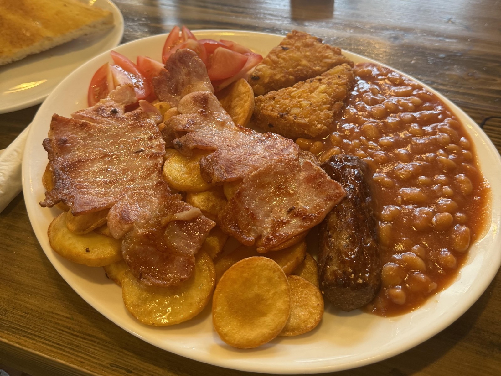 A full English breakfast with bacon, sautéed potatoes, hash browns, sausage, beans and tomatoes